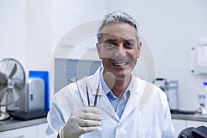 Portrait of smiling dentist holding dental tools