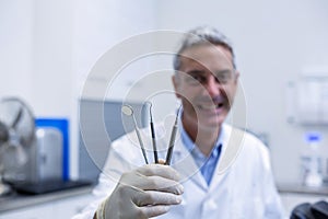 Portrait of smiling dentist holding dental tools