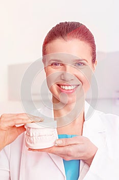 Portrait of smiling dentist holding dentures at clinic