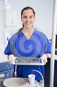 Portrait of a smiling dentist holding tray with equipment