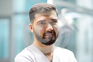 Portrait of a smiling dentist looking at camera in the office of a modern dental clinic. The doctor orthodontist is at work