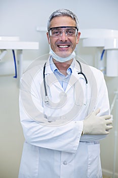 Portrait of smiling dentist standing with arms crossed