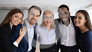 Portrait of smiling diverse colleagues hug posing in office