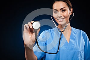 Portrait of smiling doctor in blue uniform using stethoscope