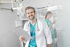 Portrait of smiling doctor holding clipboard while standing against coworker at veterinary clinic