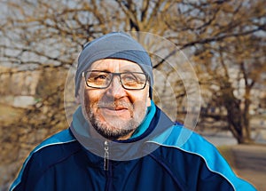 Portrait of a smiling elderly man wearing glasses, a gray hat an