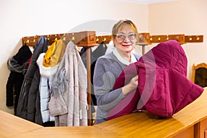 Smiling elderly woman checkroom attendant working in theater photo