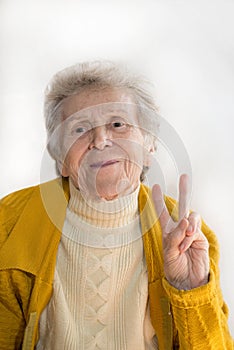 Portrait of a smiling elderly woman, hand shows peace
