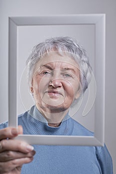 Portrait of a smiling elderly woman holding a photo frame