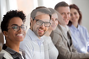 Portrait of smiling employees sit in row looking at camera