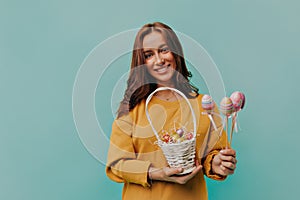 Portrait of a smiling European woman with short hair holding easter basket with eggs over isolated background.