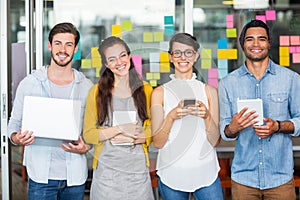 Portrait of smiling executives using laptop, mobile phone and digital tablet