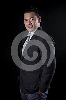 portrait smiling face happiness emotion of asian younger business man on black studio lighting