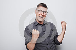 Portrait of smiling face man clenching fists and rejoicing, celebrating victory isolated on white studio background