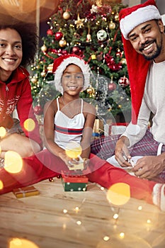 Portrait of family exchanging gifts in front of Christmas tree