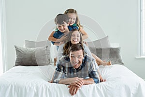 Portrait of smiling family playing on bed in bedroom