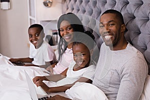 Portrait of smiling family sitting together on bed