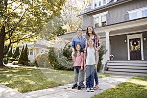 Portrait Of Smiling Family Standing In Front Of Their Home