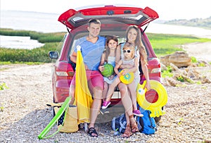 Portrait of a smiling family with two children at beach by car