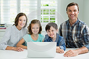 Portrait of smiling family using laptop in living room