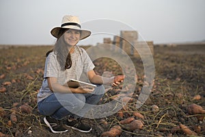 Portrait of smiling farmer using technology, young agronomist woman using tablet in agriculture with organic sweet potatoe