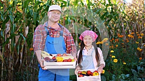 portrait of smiling farmers family , dad and daughter holding wooden boxes with different fresh vegetables, harvest on