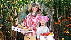 portrait of smiling farmers family , mother and daughter holding wooden boxes with different fresh vegetables, harvest
