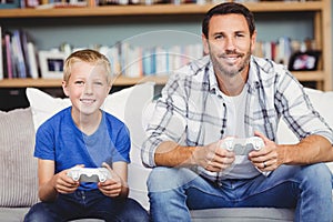 Portrait of smiling father and son playing video game