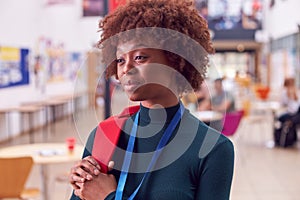 Portrait Of Smiling Female College Student In Busy Communal Campus Building