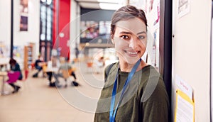 Portrait Of Smiling Female College Student In Busy Communal Campus Building