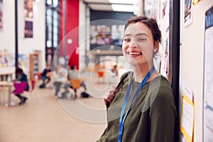 Portrait Of Smiling Female College Student In Busy Communal Campus Building