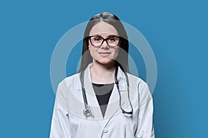 Portrait of smiling female doctor looking at camera on blue background