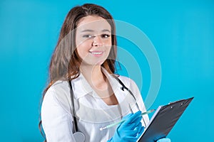 Portrait of smiling female doctor making notes about patient on the blue background