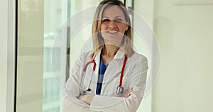 Portrait of smiling female doctor in medical uniform standing with stethoscope in clinic