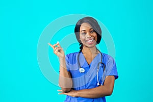 Portrait of a smiling female doctor or nurse in blue scrubs uniform looking at camera pointing