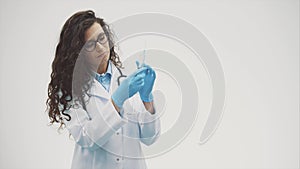 Portrait of a smiling female doctor or nurse in a white medical gown. One form of a syringe in the hands, isolated on a