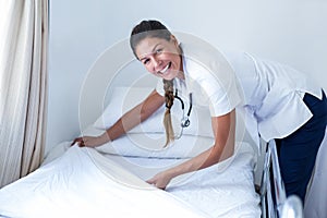 Portrait of smiling female doctor preparing the bed