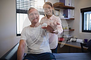 Portrait of smiling female doctor and senior male patient with arms raised