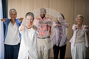 Portrait of smiling female doctor and seniors exercising