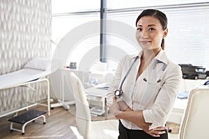 Portrait Of Smiling Female Doctor With Stethoscope Standing By Desk In Office