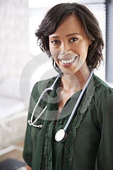 Portrait Of Smiling Female Doctor With Stethoscope Standing By Desk In Office