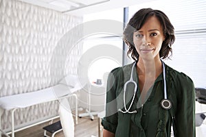 Portrait Of Smiling Female Doctor With Stethoscope Standing By Desk In Office