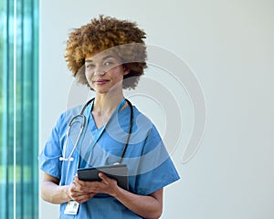 Portrait Of Smiling Female Doctor Wearing Scrubs With Digital Tablet In Hospital