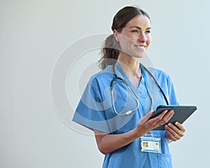 Portrait Of Smiling Female Doctor Wearing Scrubs With Digital Tablet In Hospital