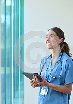 Portrait Of Smiling Female Doctor Wearing Scrubs With Digital Tablet In Hospital