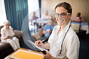 Portrait of smiling female doctor writing in file