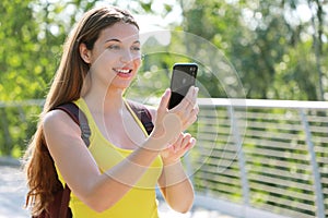 Portrait of smiling female hiker checking GPS coordinates with her smart phone looking for the right direction. Adventure, active