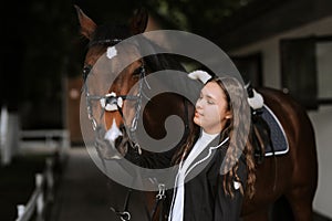 Portrait of smiling female jockey standing by horse near stable