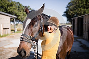 Portrait of smiling female jockey stroking horse