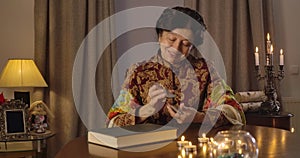Portrait of smiling female magician shuffling cards and looking at camera. Positive Caucasian senior woman telling fate